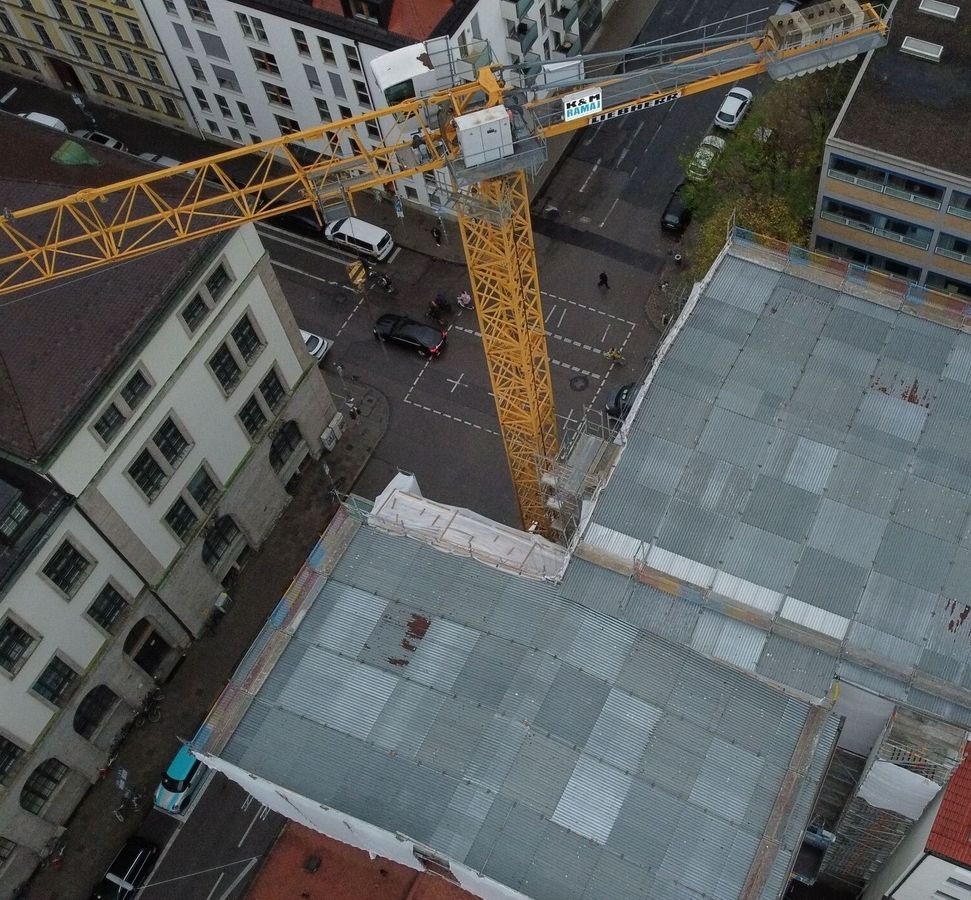 Luftaufnahme einer Baustelle mit einem großen gelben Baukran zwischen mehrstöckigen Gebäuden